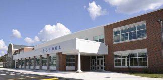 Federal Crackdown Looms On K-12 Gender Policies Modern school building with large windows and a clear sky