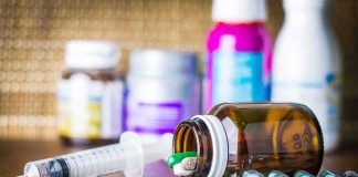 Medicine pills and syringe on table with brown bottle