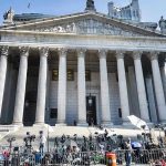 Reporters and photographers gathered outside a neoclassical courthouse