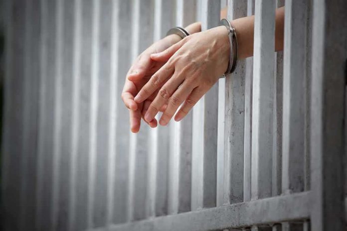 shutterstock_1018630735-2 handcuffed hands resting through prison bars
