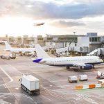 Iranian Drones Attack Kuwait Airport Airplanes at airport gates during sunset with ground vehicles and jet bridges