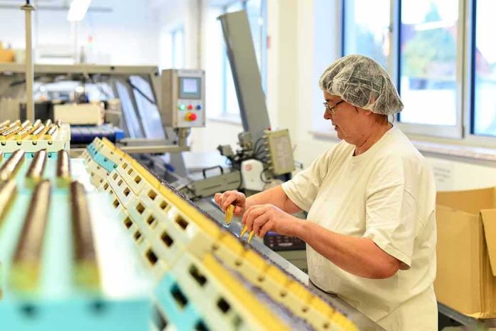 Worker in hair net inspects items on a factory conveyor line