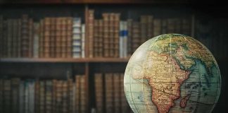 Vintage globe on wooden table in front of blurred bookshelf