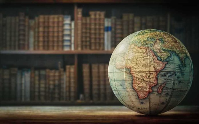 Vintage globe on wooden table in front of blurred bookshelf