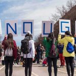 Festival Chaos: Shooters Vanish Group of people holding signs spelling ENOUGH at a street protest