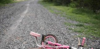 Candy Sedation Scheme On Kids- Texas Court Erupts Pink children's bicycle with training wheels lying on a gravel path