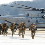 Cyber Recruits Score $15K – Why Now? Soldiers disembark and walk past a large military helicopter