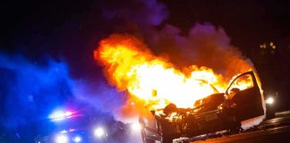 Burning car on a dark street at night