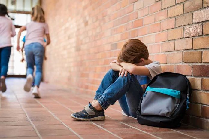 shutterstock_1136889179 boy sitting against brick wall with head on arms and backpack