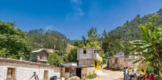 Rural village street with people gathered and hills in the background