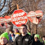 Judge Hits Pause on Abortion Pill Fight Protesters holding anti-abortion signs at an outdoor rally