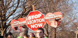Judge Hits Pause on Abortion Pill Fight Protesters holding anti-abortion signs at an outdoor rally