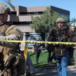 Tactical police officers behind yellow caution tape at an outdoor scene