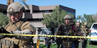 Tactical police officers behind yellow caution tape at an outdoor scene