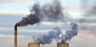 Carbon Rollback IGNITES Legal War Industrial power plant with smokestack and cooling towers emitting smoke