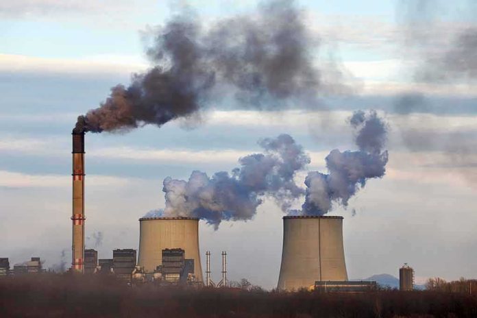 shutterstock_1555865300 Industrial power plant with smokestack and cooling towers emitting smoke