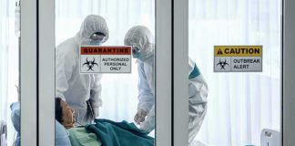 Healthcare workers in hazmat suits treat a patient in a quarantine room