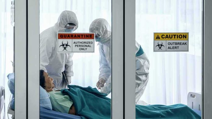 Healthcare workers in hazmat suits treat a patient in a quarantine room