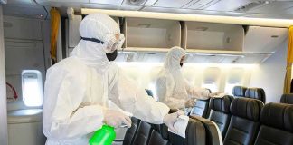 Workers in hazmat suits disinfecting airplane cabin seats