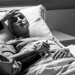 CDC Under Fire: Hantavirus on Luxury Cruise Patient in hospital bed with nasal oxygen held by visitor