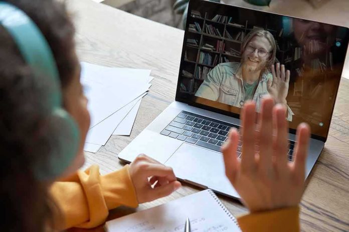 Student in headphones waving at a person on a laptop video call