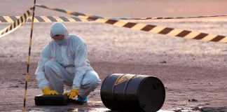 Major Incident Near US Air Base Hazmat worker kneeling near a fallen barrel at a cordoned-off site