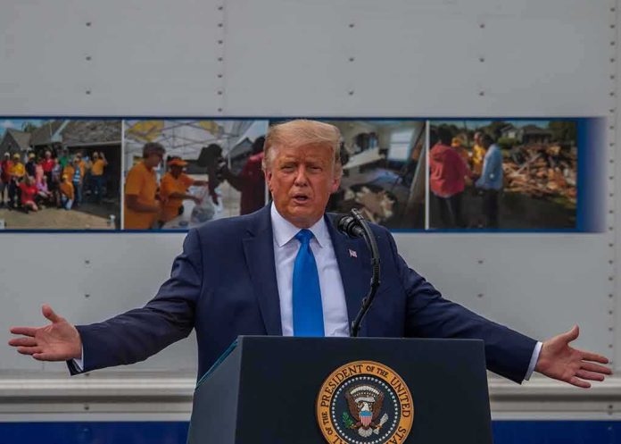 shutterstock_1804636972-2 Donald Trump speaks at a podium with arms outstretched
