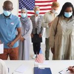 Voters wearing masks stand in line at a polling station
