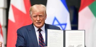 Donald Trump holding a signed document at a ceremony