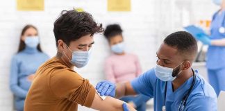 Healthcare worker gives vaccination to masked patient in clinic