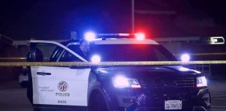 Police SUV with flashing lights at night behind yellow tape