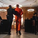 Ohio Courthouse Mayhem: Throat Punch, Broken Bones Prisoner in orange jumpsuit escorted by officer in a courtroom