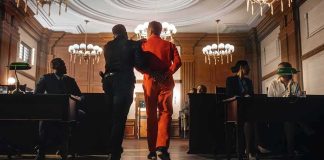 Ohio Courthouse Mayhem: Throat Punch, Broken Bones Prisoner in orange jumpsuit escorted by officer in a courtroom