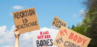 Men Pregnant? Congress Clip Ignites Firestorm Protesters hold cardboard signs at a rally outdoors