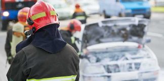 Firefighter near foam-covered car with open hood