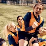 Women's soccer teammates celebrate lifting a player