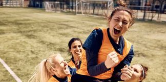 Women's soccer teammates celebrate lifting a player