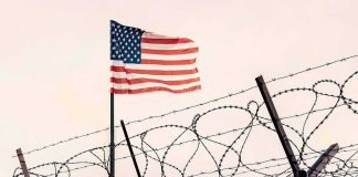American flag above barbed wire fence