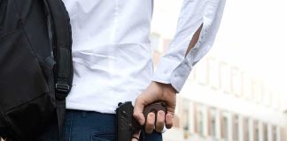 Sheriff Clears Dad – NAACP Demands Action person holding a handgun behind their back near a building