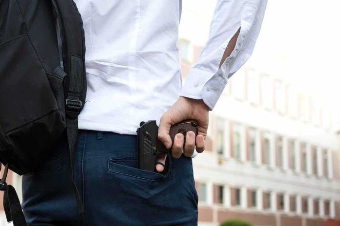 shutterstock_2199457537 person holding a handgun behind their back near a building