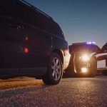 Police Chief Indicted: 70 Shocking Counts Police officer at patrol car during traffic stop at dusk
