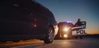 Police officer at patrol car during traffic stop at dusk