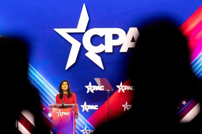 Woman in red speaks at podium on brightly lit conference stage