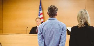 Travis Kelce Named In Shocking Ponzi Fallout Defendant in handcuffs stands before a judge in a courtroom
