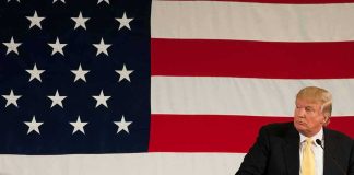 Donald Trump at a podium with a large American flag backdrop