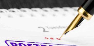 Fountain pen over calendar with postponed stamp