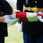 Non-Combat Death – Name Revealed Military personnel folding a flag during a ceremonial event
