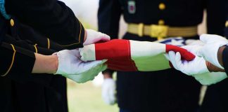 Non-Combat Death – Name Revealed Military personnel folding a flag during a ceremonial event