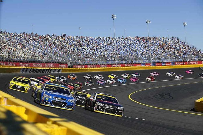 shutterstock_497557876 Stock cars racing on a banked track with grandstands in background