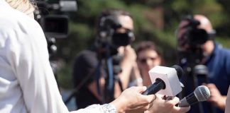 Reporters hold microphones during an outdoor press interview